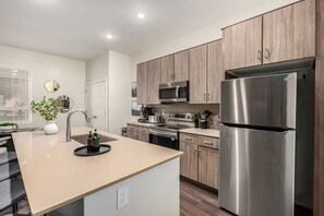 Een moderne keuken met houten kasten, roestvrijstalen apparatuur en een centraal eiland met een spoelbak.
