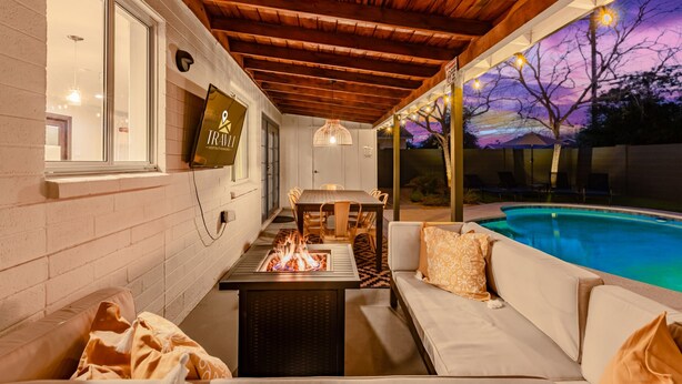 A cozy outdoor seating area with a fire feature, a pool, and a wooden ceiling. - Desert Diamond Oasis Private Pool Bar Games (Scottsdale)