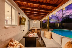 A cozy outdoor seating area with a fire feature, a pool, and a wooden ceiling. - Desert Diamond Oasis Private Pool Bar Games (Scottsdale)