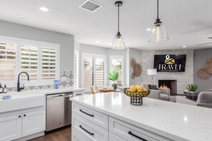 A modern kitchen with white cabinetry, a central island, and pendant lighting. - Greenway Park Retreat Al-fresco Living Heated Pool (Scottsdale)