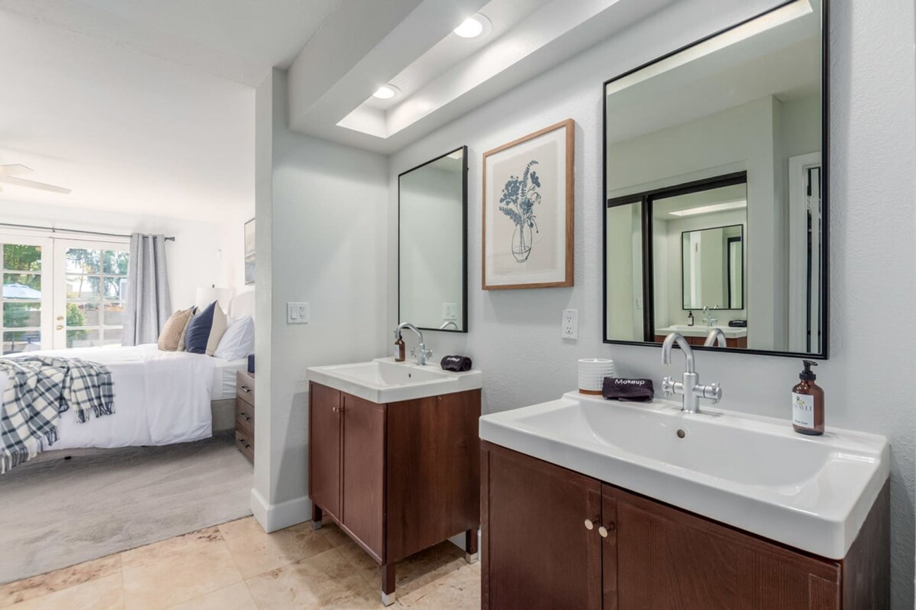 Un baño moderno con dos lavabos, un espejo grande y una cama con vistas al exterior.