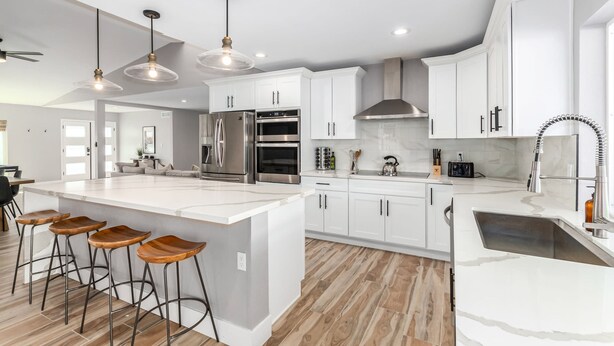 A modern kitchen with white cabinets, stainless steel appliances, and wooden bar stools. - Agave on Cactus Private Pool Firepit Sleeps 10 (Scottsdale)