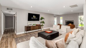 A modern living room with a fireplace, a flat-screen TV, and a cozy seating area. - Agave on Cactus Private Pool Firepit Sleeps 10 (Scottsdale)