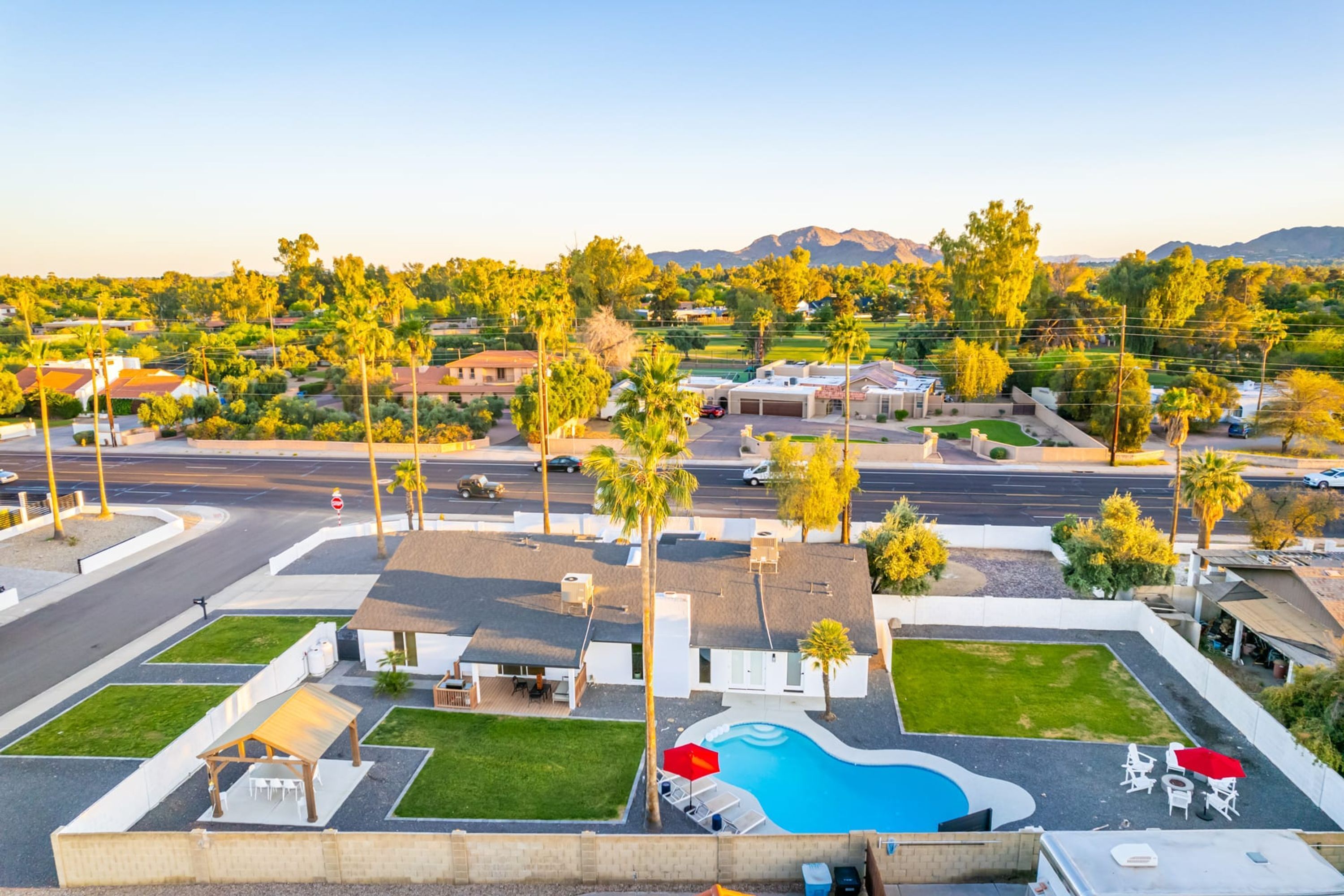 A residential area with a swimming pool, palm trees, and houses.