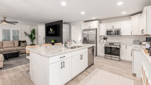 A modern kitchen with white cabinets, stainless steel appliances, and a central island. - Desert Rose Retreat Heated Pool 2 Masters Gameroom (Scottsdale)
