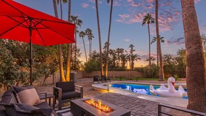 A patio area with a fire pit, outdoor furniture, and a swimming pool with a swan float. - Doce Palmas Free Htd Pool Spa Putt Grn (Scottsdale)