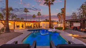 A pool area with a swan float, palm trees, and outdoor seating. - Doce Palmas Free Htd Pool Spa Putt Grn (Scottsdale)