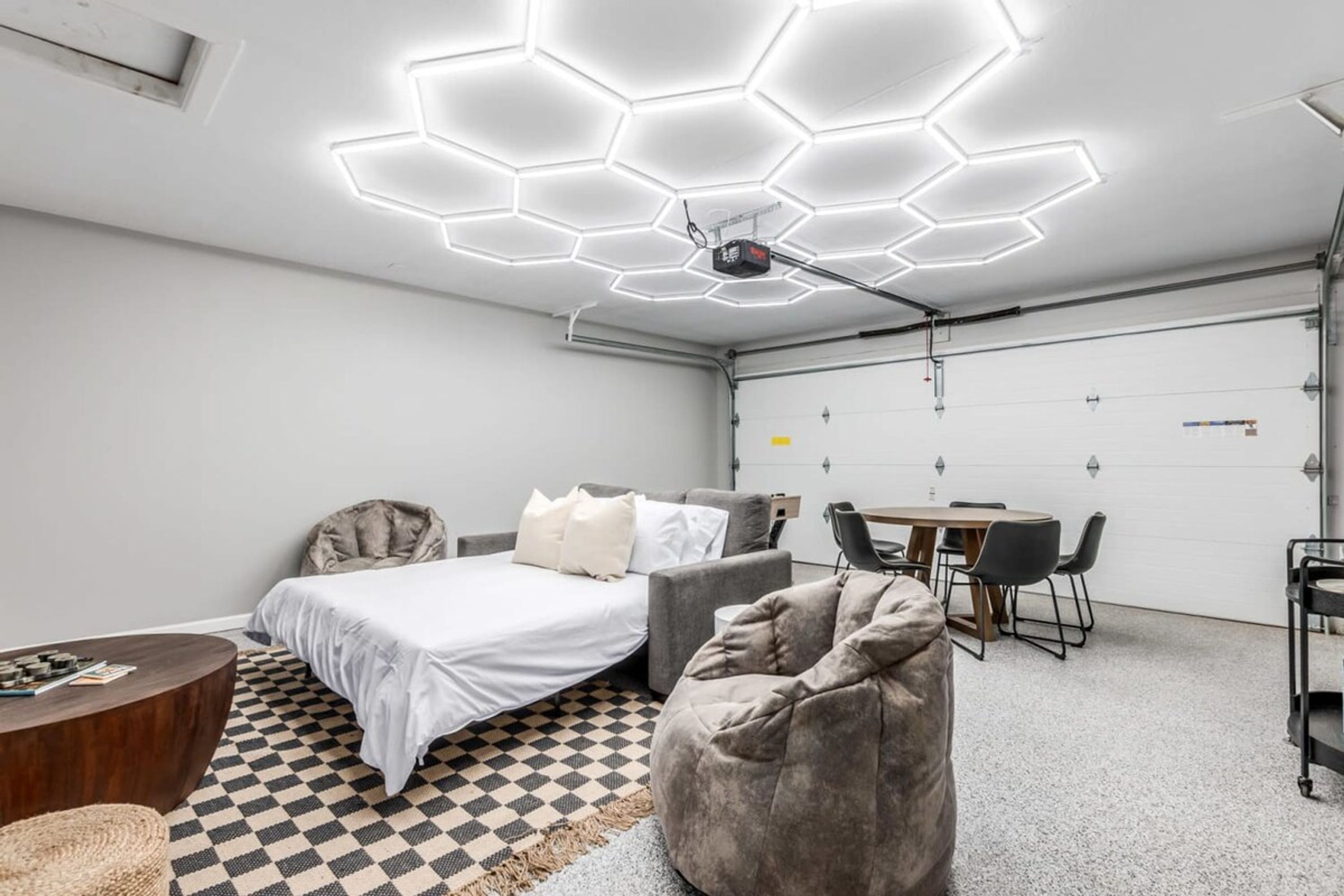 A modern, well-lit room with a bed, seating area, and a dining table.
