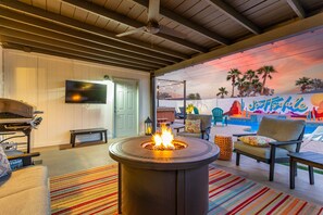 A cozy outdoor seating area with a fire pit, comfortable chairs, and a colorful mural in the background. - SW Modern Retreat 2 Masters Pool Hottub Firepit (Scottsdale)