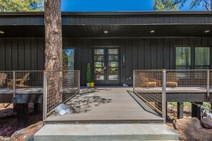A modern building with a wooden exterior, a front door, and a covered walkway with seating areas and a tree. - Le Cabin Noir LUX Alpine Retreat Spa BBQ (Flagstaff)