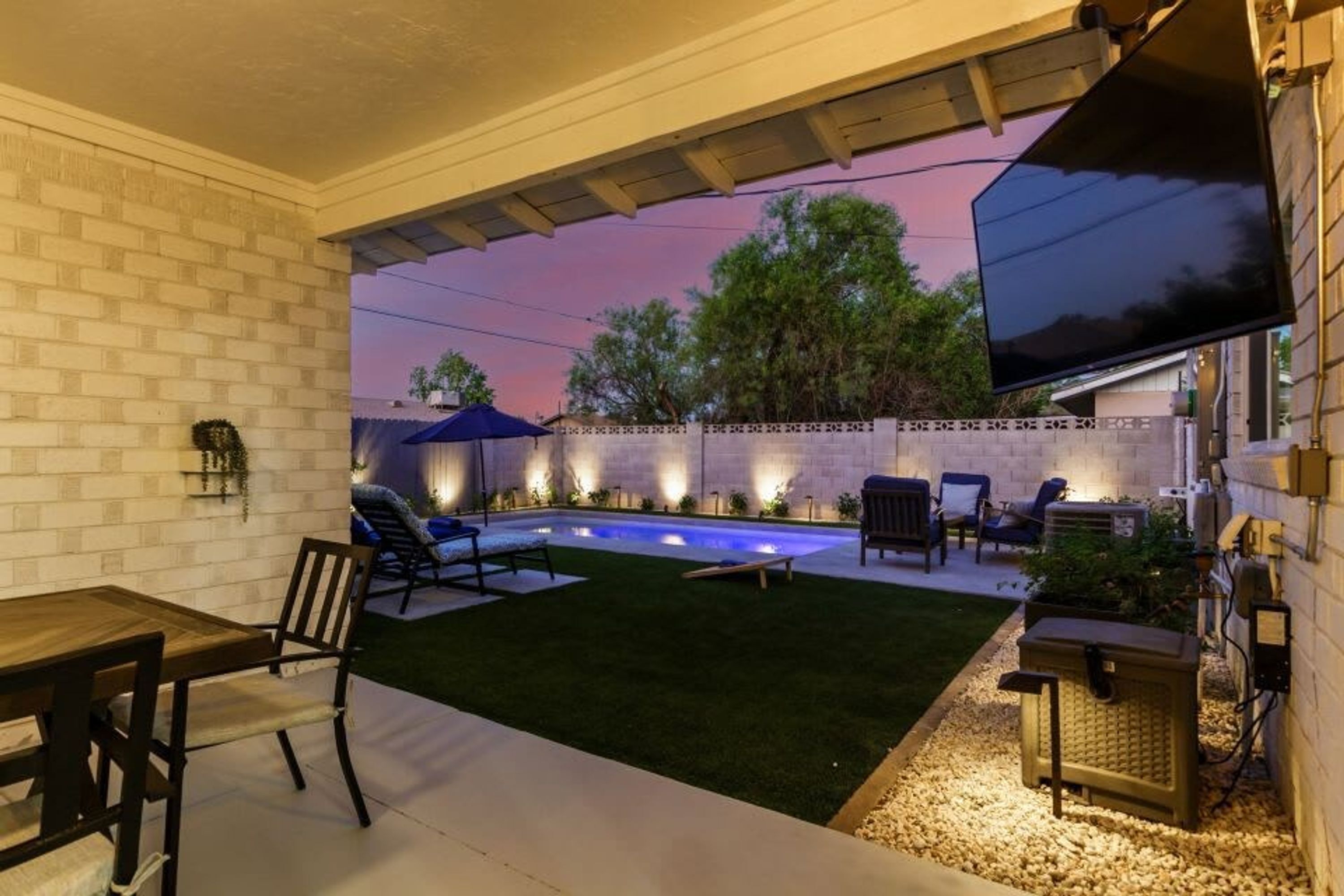 A patio area with a pool, outdoor furniture, and a TV screen.