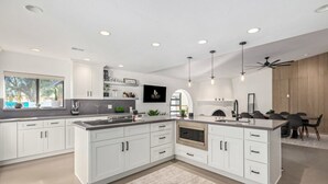 A modern kitchen with white cabinetry, a central island, and built-in appliances. - 5BR Resort-style Oasis 2 Primary s Cabana Gameroom (Chandler)