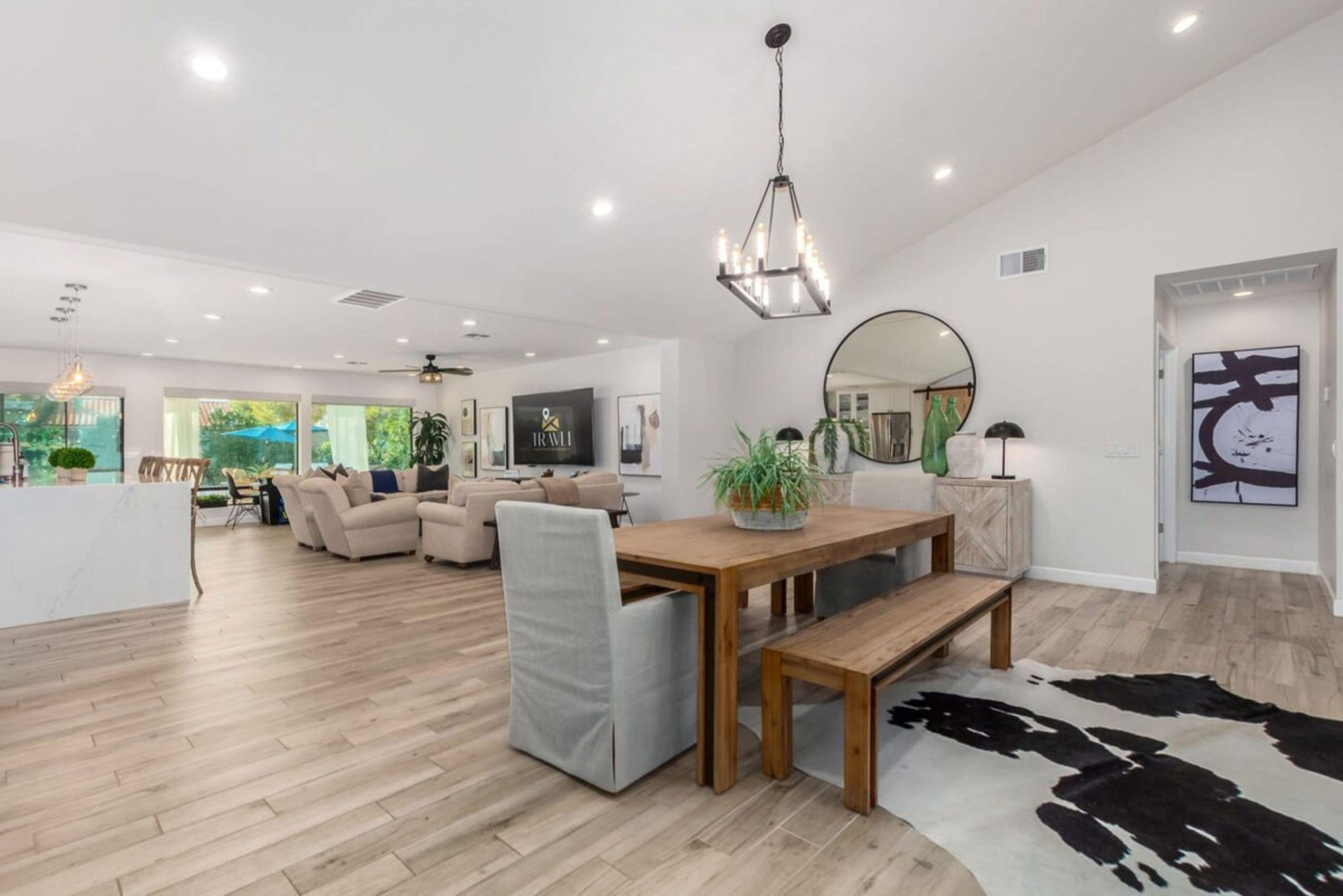 A spacious living area with a wooden dining table, a sofa, and a large mirror.