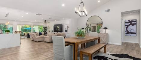 A spacious living area with a wooden dining table, a sofa, and a large mirror.