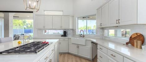 A modern kitchen with white cabinetry, a large island, and a view of the outdoors.