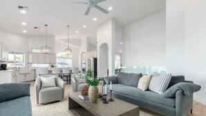A spacious living area with a grey sofa, a coffee table, and a dining area in the background. - Sweetwater Resort Estate Tennis Pool Spa Vball (Scottsdale)