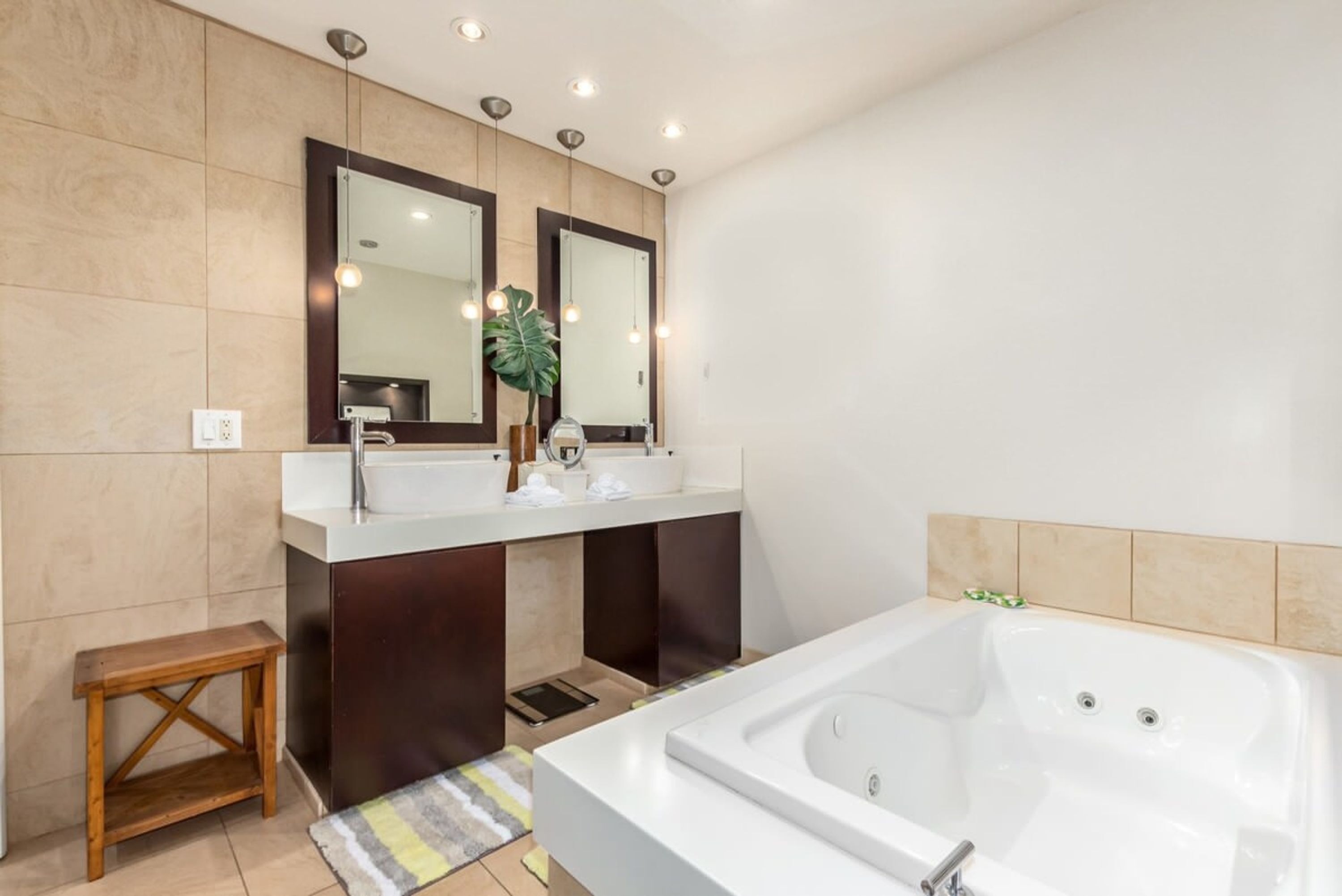 A modern bathroom with a large bathtub, two sinks, and a mirror above each sink.