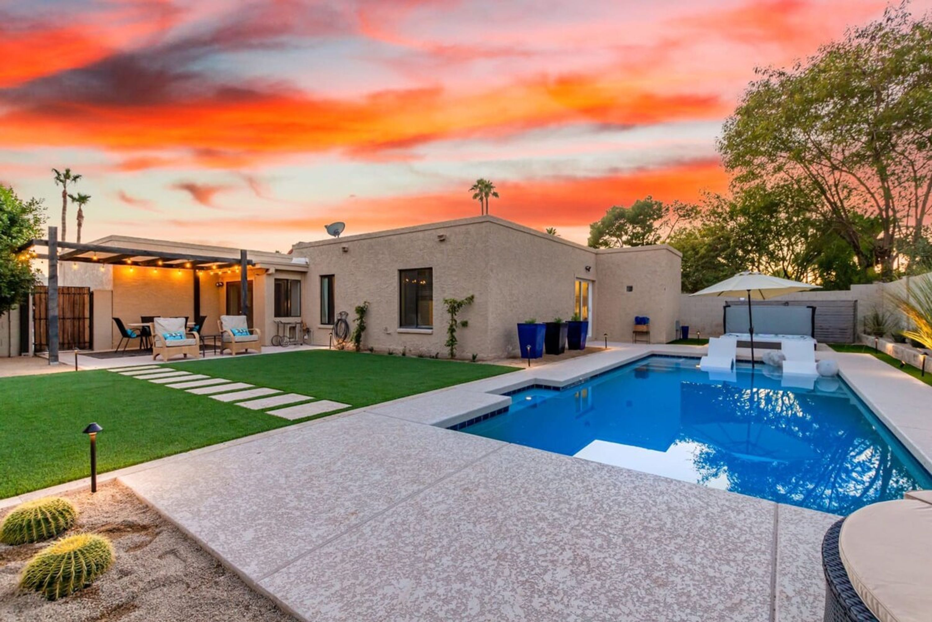 Una casa moderna con piscina, patio e prato curato.