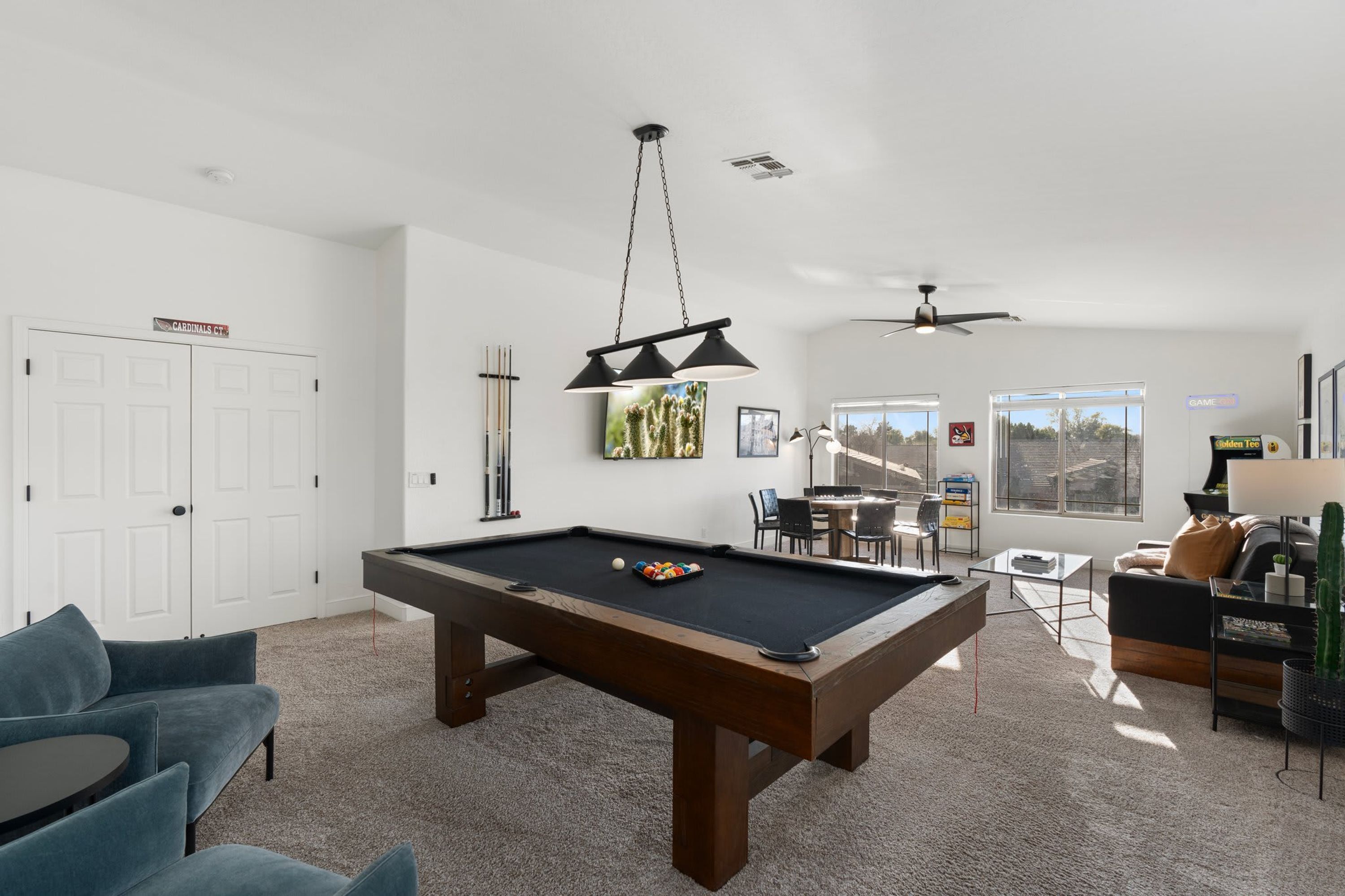 A modern living room with a pool table, a blue sofa, a coffee table, and a cactus plant.