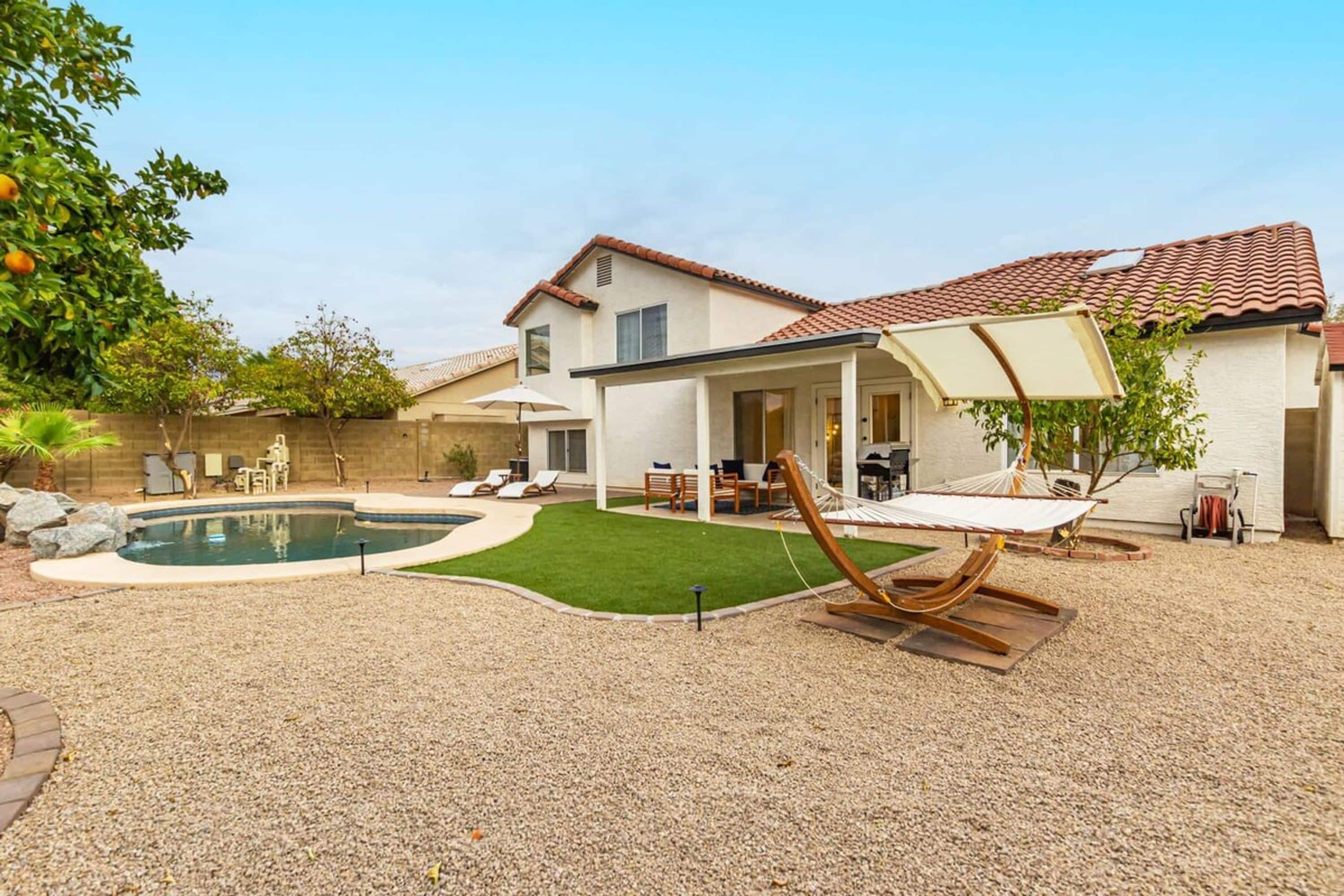 A residential property with a swimming pool, a covered patio, and a hammock.