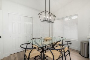 A dining area with a glass table and black metal chairs, a hanging light fixture, and a window with blinds. - 5BR Citrus Estate Sleeps 13 Free Htd Pool Gameroom (Mesa)