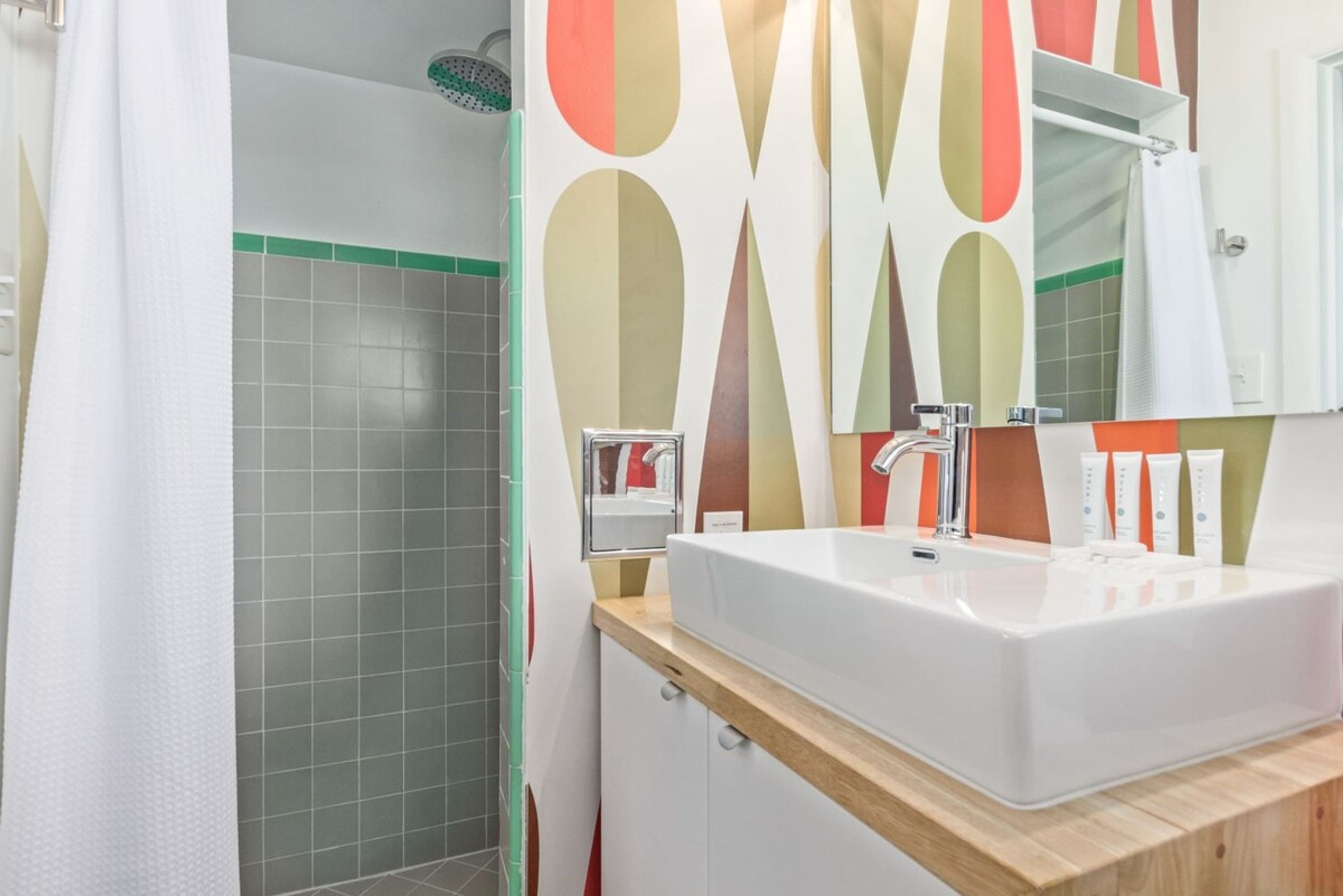 A bathroom with a shower, a sink, and a mirror.