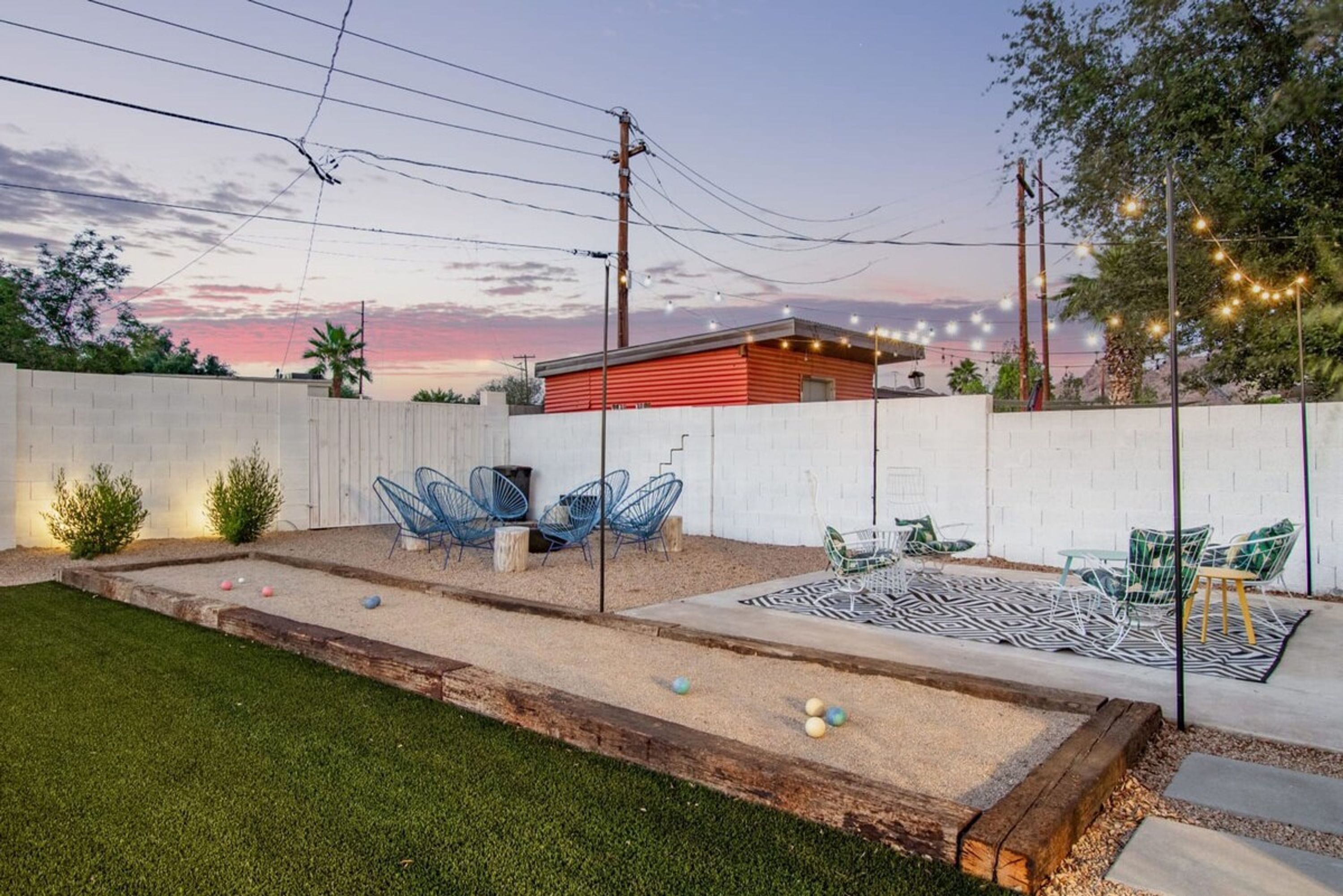 A backyard with a red building, outdoor seating, and a well-maintained lawn.