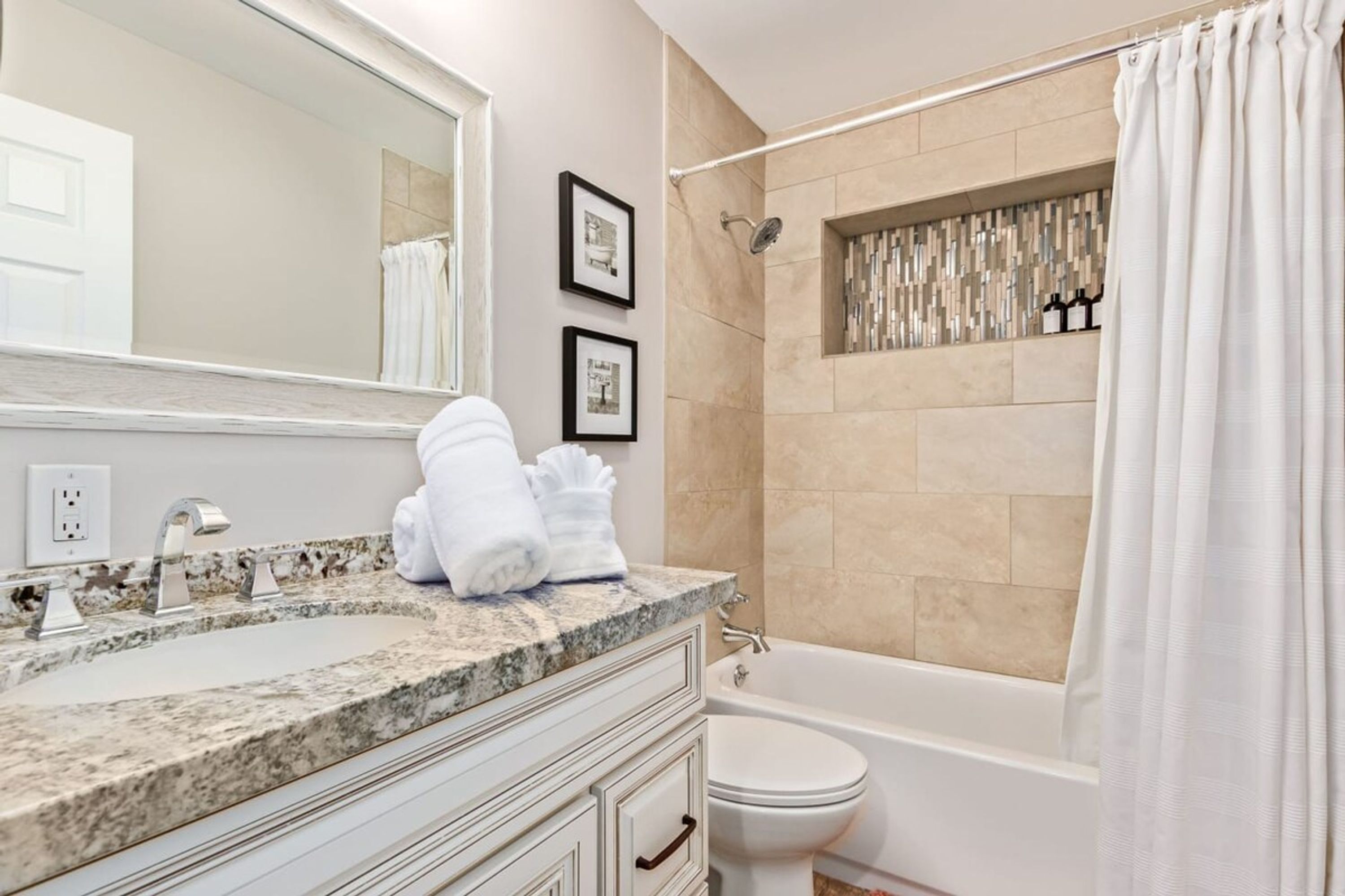 Une salle de bain moderne avec un comptoir en granit, un lavabo blanc, une baignoire et une douche.