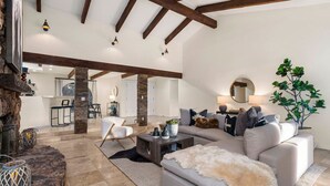 A spacious living room with a large sofa, a coffee table, and a fireplace. There is a dining area in the background with a table and chairs. - Serenity Retreat Sedona Hot Tub Games Firepit (Sedona)