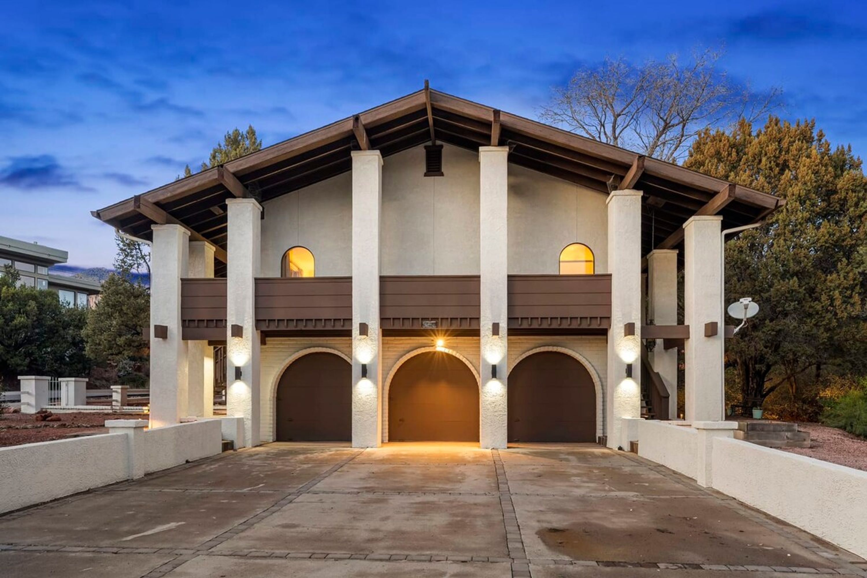 A modern building with a central arched entrance, two visible upper levels, and a symmetrical facade with columns and arches.