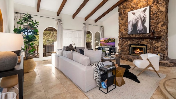 A spacious living room with a stone fireplace, a white sofa, and a large painting of a horse. - Serenity Retreat Sedona Hot Tub Games Firepit (Sedona)