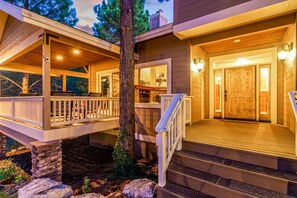 A two-story house with a wooden deck, stone pillars, and a large wooden door. - Amberwood Estate w 5 Showers Spa Mtn Views (Flagstaff)