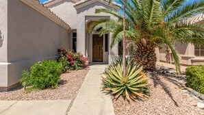 A house with a stucco exterior, a palm tree, and a pathway leading to the entrance. - Walk 2 TPC Mayo Swim Putt Grill Heated Pool (Scottsdale)