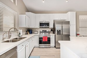 Une cuisine moderne avec des armoires blanches, des appareils en acier inoxydable et un îlot central.