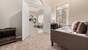 A bedroom with a bed, a desk, and a chair. There is a door leading to another room. - Walk 2 TPC Mayo Swim Putt Grill Heated Pool (Scottsdale)