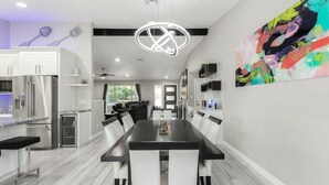 A modern kitchen with a dining area, stainless steel appliances, and a large abstract painting on the wall. - Kings Lux Escape Free Htd Pool Cabana BBQ Firepit (Scottsdale)