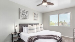 A bedroom with a bed, a nightstand, a ceiling fan, and two wall-mounted decorative items. - Rustic Modern Townhouse Old Town 4 Heated Pools (Scottsdale)