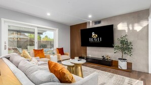 A modern living room with a sofa, coffee table, and TV. - Corrine Family Oasis Pool Putt Grn Bigtoy (Scottsdale)