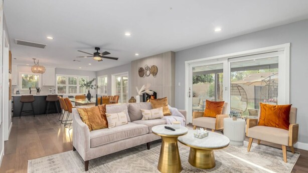 A spacious living area with a sofa, coffee table, and chairs, a kitchen in the background, and large windows. - Corrine Family Oasis Pool Putt Grn Bigtoy (Scottsdale)