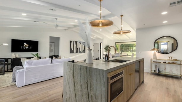 A modern kitchen with a marble island, wooden cabinets, and pendant lighting. - The Kingsley Custom Heated Pool Chef Kitchen Chess (Scottsdale)