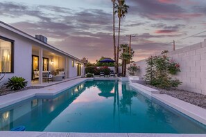 Une maison moderne dotée d’une piscine, de mobilier d’extérieur et d’un espace patio.
