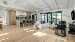 A spacious living area with a white sofa, black chairs, a coffee table, and a view of the ocean. - The Kingsley Custom Heated Pool Chef Kitchen Chess (Scottsdale)