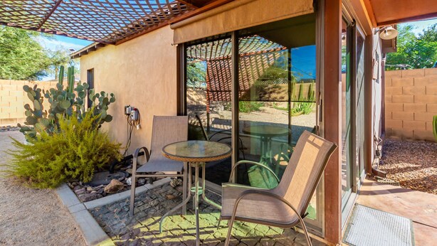 An outdoor patio with a glass table and chairs, a cactus plant, and a wooden pergola. - Coronado Casita - Mins to DT Airport Hospitals (Phoenix)