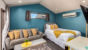 A bedroom with a bed, a sofa, a small table, and an air conditioning unit. - Coronado Casita - Mins to DT Airport Hospitals (Phoenix)