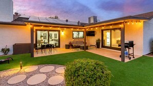 Une maison moderne dotée d’un patio, d’un espace salon extérieur et d’un coin barbecue.