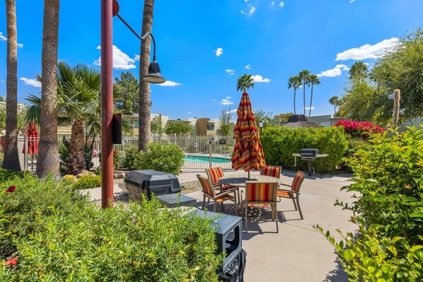 Un patio exterior con piscina, sillas de descanso y una parrilla.