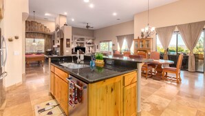 A spacious kitchen with wooden cabinets, a central island, and a dining area with chairs and a table. - Desert Foothils Rustic Resort Oasis w Pool Spa (Scottsdale)