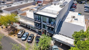 Un immeuble à plusieurs étages, doté d’un toit plat, de grandes fenêtres et d’un parking où sont stationnées plusieurs voitures.