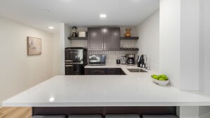 Une cuisine moderne dotée d’un îlot central, d’appareils électroménagers intégrés et d’un design minimaliste.