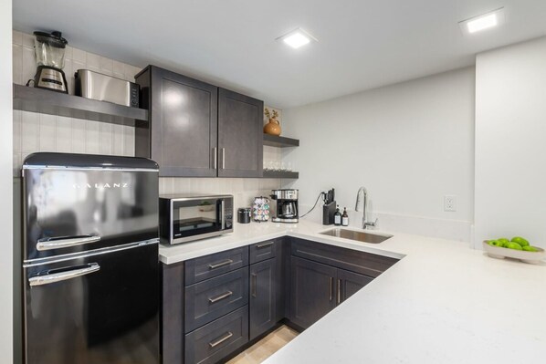 A modern kitchen with dark cabinets, stainless steel appliances, and a white countertop. - Old Town Studio Gym Biz Center Walk 2 Everything (Scottsdale)